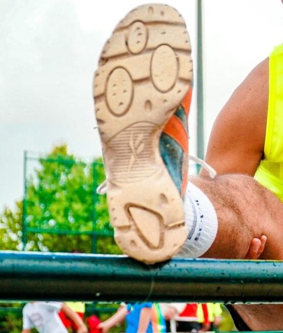 Senior man stretches before outdoor track run. Bright day for fitness.